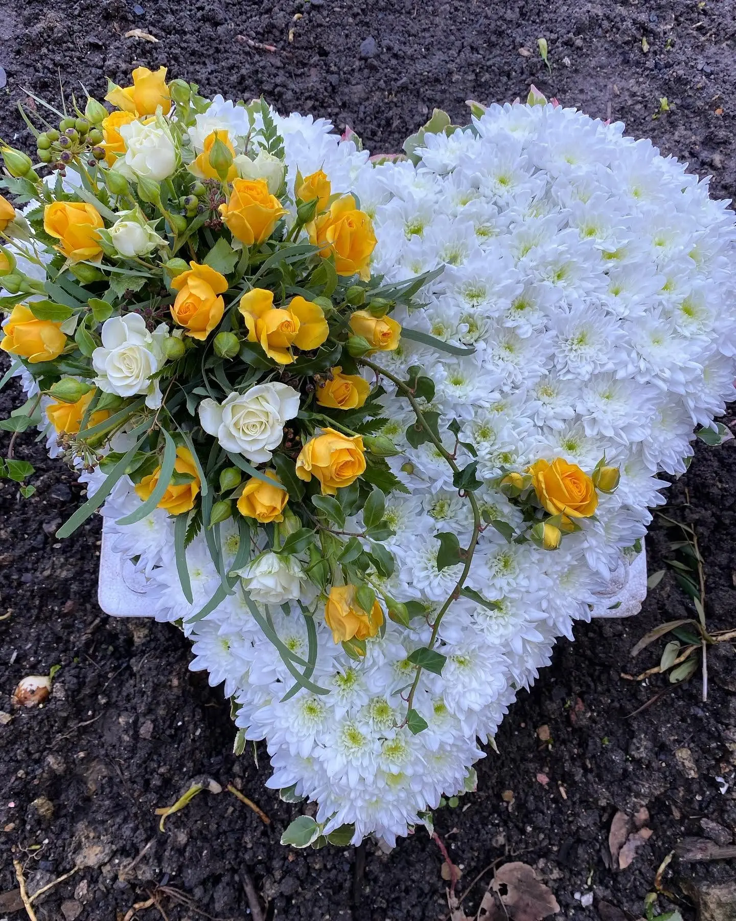 Heart-shaped yellow and white funeral flower tribute