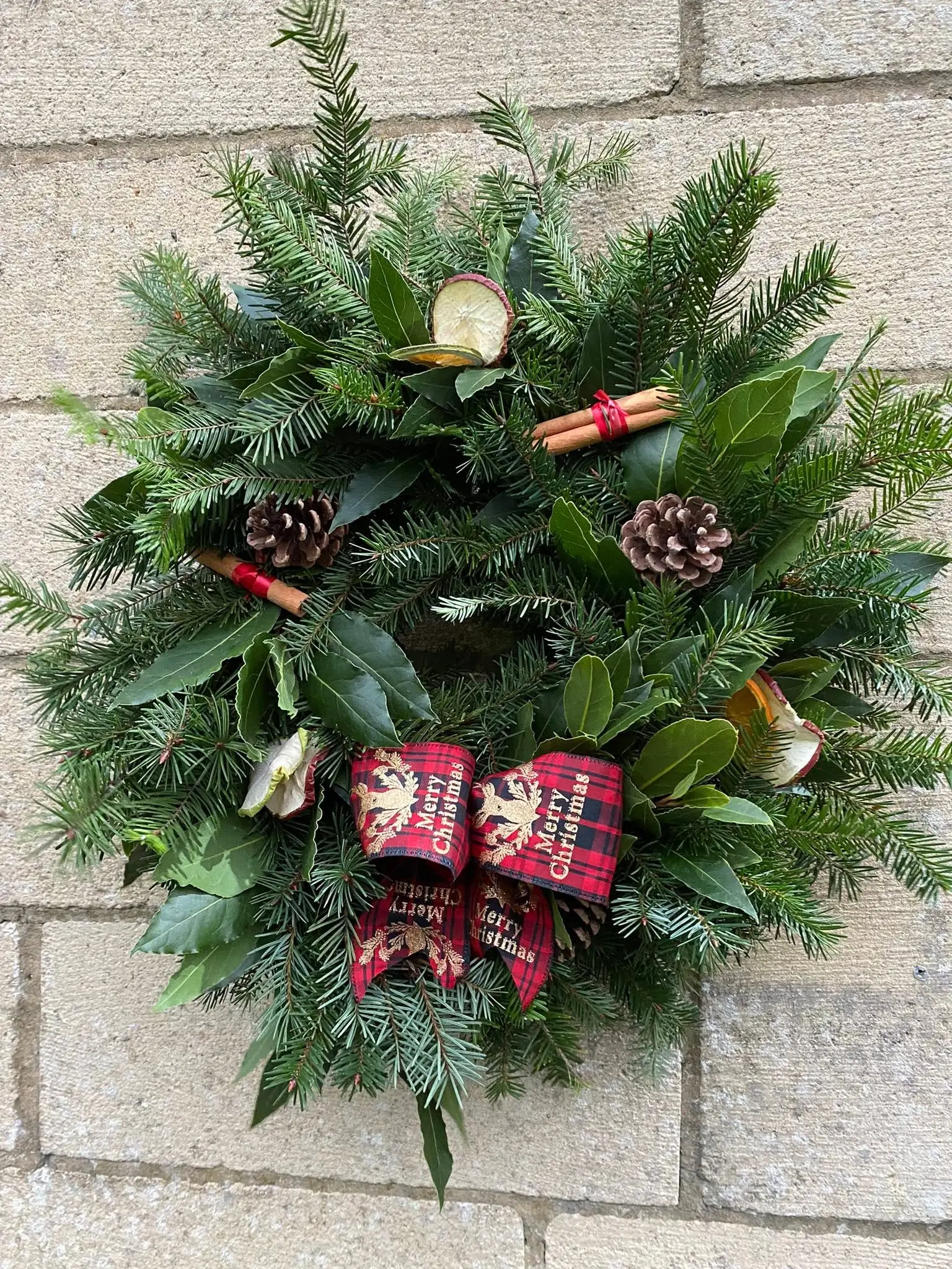 Handmade evergreen Christmas wreath with pine cones and ribbon
